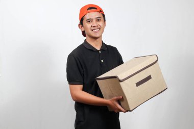 Kutu taşıyan arkadaş canlısı teslimatçı kapına gülümseyerek hızlı bir nakliyat ve kusursuz bir servis sunuyor.