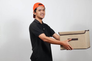 Kutu taşıyan arkadaş canlısı teslimatçı kapına gülümseyerek hızlı bir nakliyat ve kusursuz bir servis sunuyor.