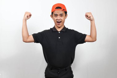 Hevesli genç bir adam beyaz bir arka plana karşı neşeli bir ifadeyle kaslarını esnetiyor.