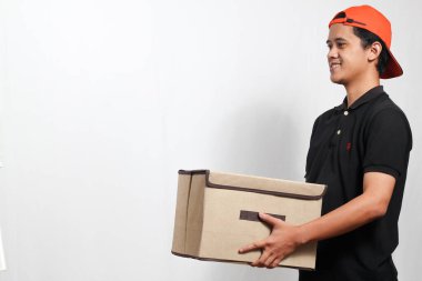 Turuncu şapkalı etkili teslimatçı temiz beyaz arka plana özen göstererek kutu taşıyor.