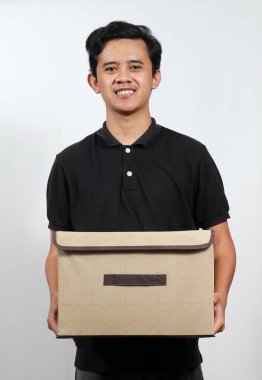 Neşeli genç adam depo kutusunu temiz bir stüdyo ortamında teslimat ya da organizasyon için hazır tutuyor.