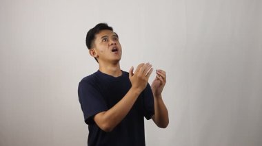 Hasta Asyalı adam hapşırır ve virüsün yayılmasını önlemek için iki eliyle kapatır..