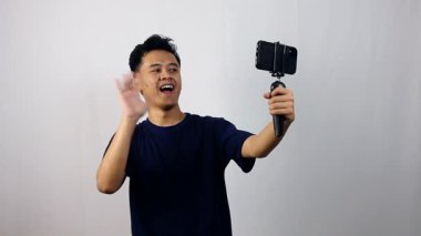 Genç Asyalı adam coşkuyla sosyal medya içeriği yaratıyor.