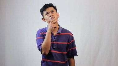 Mor çizgili gömlek giyen Asyalı genç adam çok düşünüyor.