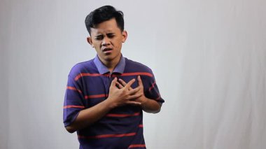 Asyalı bir adam göğsünü tutarak ani kalp krizi geçiriyor.