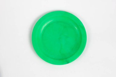 Beyaz arka planda yeşil plastik bir plaka, basit ve minimalist bir üst görünüm. Yemek hazırlama, tek kullanımlık sofra takımı veya piknik ayarları için ideal.