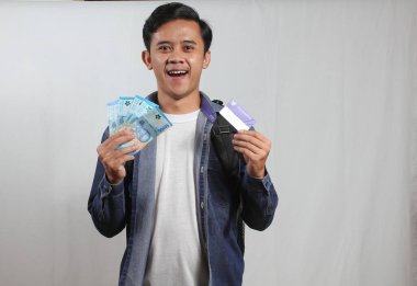 Endonezya akıllı kartı tutan genç bir öğrenci ve buruşuk beyaz kumaş arka planda izole edilmiş Endonezya banknotları. Fakir öğrenciler için devlet yardımı kavramı