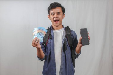 Sırt çantalı genç bir adam, Endonezya Rupiah 'ının elinde macerasına hazır olmasından heyecan duyuyor. Olasılıkları, seyahat ve finansal özgürlüğü hayal edin.!