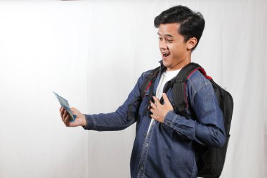 Sırt çantalı genç Asyalı öğrenci elinde para tutarken gülümsüyor ve minnet duyuyor. Ekonomi, başarı, başarı ve finansal özgürlük kavramı.