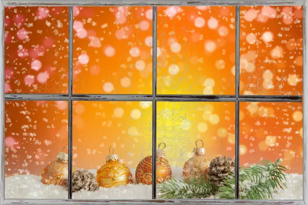 Altın mücevherler, turuncu arka planlı bir pencerenin arkasındaki karda yatıyor..