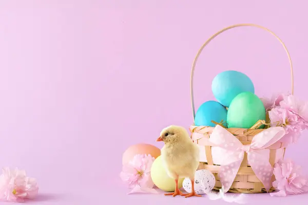 Paskalya sepeti, pembe bir arka plan üzerine boyanmış renkli paskalya yumurtalarıyla dolu.