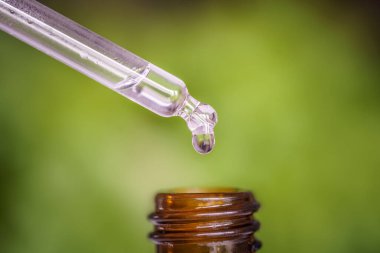 Açık arkaplanda serum ve şişe olan şeffaf bir pipet..