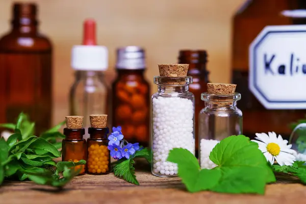 Masada bir sürü ilaç ve küreyle dolu tıbbi cam şişeler var. Homeopati konzepti.
