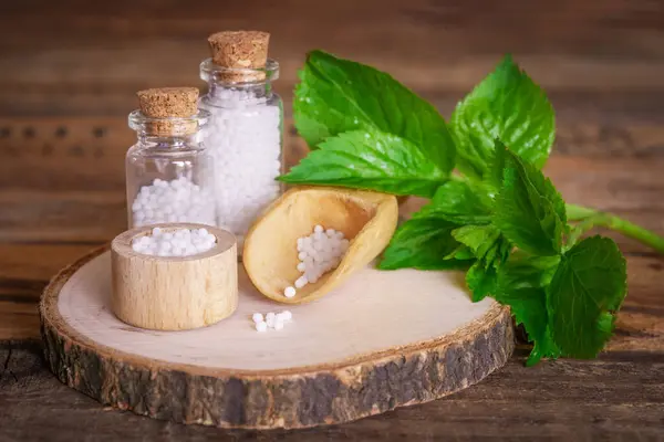 Tahta masadaki küreyle dolu tıbbi cam şişeler. Yapraklar ve çiçeklerle süsleme.