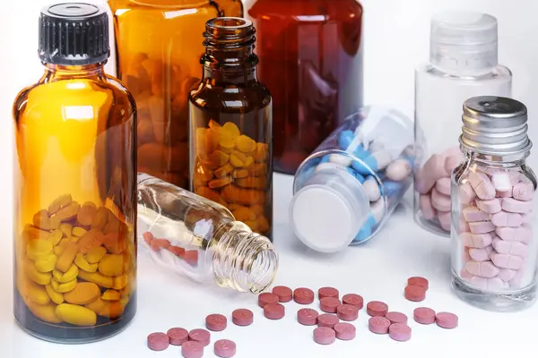 Sarı ve beyaz ilaç şişeleri ve haplar..