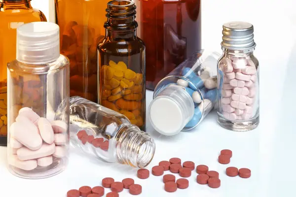 Sarı ve beyaz ilaç şişeleri ve haplar..