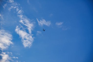 Dağınık beyaz bulutlarla açık mavi gökyüzünde uçan küçük bir uçak..