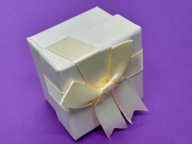 Mor arka planı olan beyaz bir hediye kutusu..