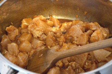 Doğranmış tavuk göğsü parçaları tencerede güveç gibi pişiriliyor, yakın çekim mutfak manzarası..