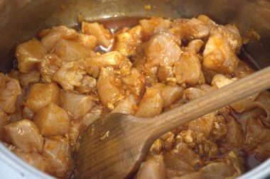 Doğranmış tavuk göğsü parçaları tencerede güveç gibi pişiriliyor, yakın çekim mutfak manzarası..