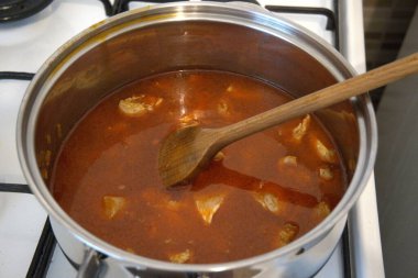 Doğranmış tavuk göğsü parçaları tencerede güveç gibi pişiriliyor, yakın çekim mutfak manzarası..