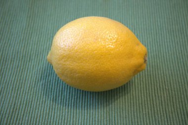 Yeşil arkaplana yerleştirilmiş koca bir limon. Metin ya da tasarım için yeterli kopya alanına sahip yakın çekim.
