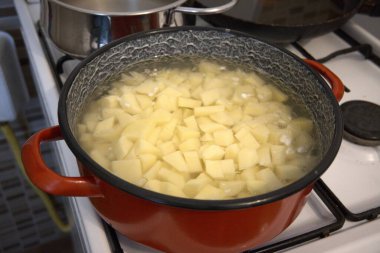 Fırında pişen bir tencerede taze doğranmış patates, yakın planda çekilmiş. Ev yapımı yemek ve konfor konsepti.