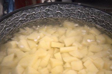 Fırında pişen bir tencerede taze doğranmış patates, yakın planda çekilmiş. Ev yapımı yemek ve konfor konsepti.