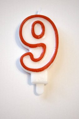 Tek sayılı dokuz doğum günü mumu yakından çekilmiş, beyaz bir arka planda izole edilmiş. Doğum günü kutlamaları ve yıldönümleri için ideal..