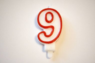 Tek sayılı dokuz doğum günü mumu yakından çekilmiş, beyaz bir arka planda izole edilmiş. Doğum günü kutlamaları ve yıldönümleri için ideal..