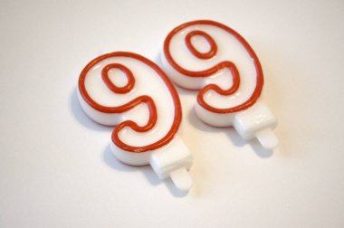 Pembe ve beyaz 99 numaralı doğum günü mumunun yakın plan temiz beyaz arka planda izole edilmiş hali..