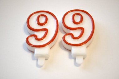 Pembe ve beyaz 99 numaralı doğum günü mumunun yakın plan temiz beyaz arka planda izole edilmiş hali..