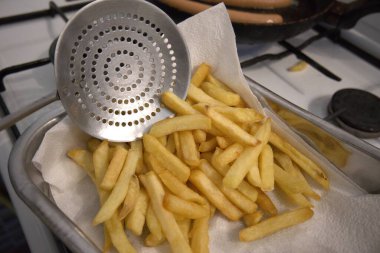 Pişirme kabında kağıt havlunun üzerinde duran kızarmış patates çubukları..