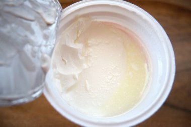 Açık plastik bir kapta, yiyecek ve süt ürünleri için izole edilmiş ekşi krema yakın plan..