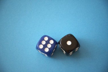 Bir mavi zarın kompozisyonu, altı nokta ve bir siyah zarın tek bir noktayı göstermesi, mavi arkaplanda fotokopi alanı ile..