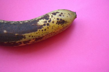 Pembe arkaplana yerleştirilmiş kahverengi bir muz tasarım için fotokopi alanı ile yakın plan çekilmiş..