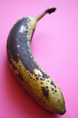 Pembe arkaplana yerleştirilmiş kahverengi bir muz tasarım için fotokopi alanı ile yakın plan çekilmiş..