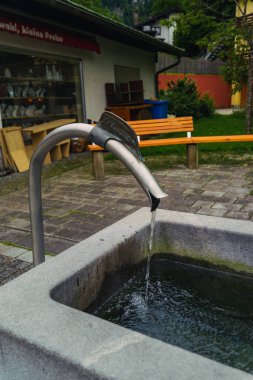 Tatlı su, yemyeşil yemyeşil ve basit ahşap banklarla çevrili metal bir oluktan yavaşça taştan bir oluğa akar ve barışçıl bir atmosfer yaratır. Konigssee Bavyera Alman Alpleri