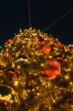Parlayan ışıklar ve ziynetlerle süslenmiş altın Noel ağacı şenlikli bir akşam ortamında. Yüksek kalite fotoğraf
