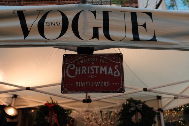 Christmas market tent with festive signage and decorations featuring Vogue holiday branding. High quality photo clipart