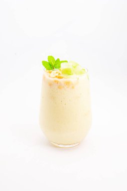 Mısır gevreğiyle kaplı kremalı muzlu smoothie ve beyaz arka planda temiz bardakta servis edilen taze nane şekeri. Yüksek kalite fotoğraf