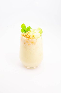 Mısır gevreğiyle kaplı kremalı muzlu smoothie ve beyaz arka planda temiz bardakta servis edilen taze nane şekeri. Yüksek kalite fotoğraf