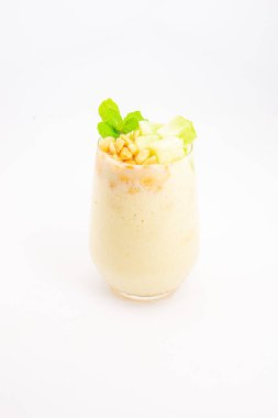 Mısır gevreğiyle kaplı kremalı muzlu smoothie ve beyaz arka planda temiz bardakta servis edilen taze nane şekeri. Yüksek kalite fotoğraf