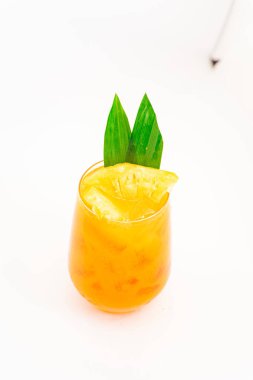 Turuncu turunçgil kokteyli, şeffaf camla servis edilen tropikal yaprak garnitürü, temiz beyaz arka planda buzun üzerinde. Yüksek kalite fotoğraf