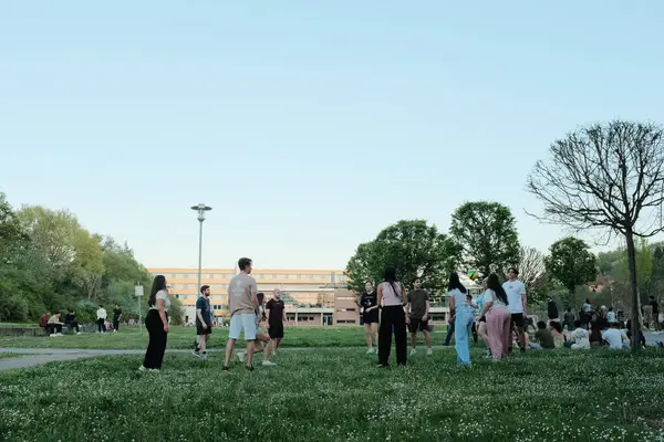 Baharın güneşli bir gününde açık gökyüzü altında halka açık yeşil parkta oynayan ve dinlenen insanlar. Yüksek kalite fotoğraf