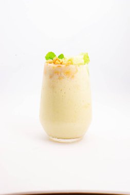 Mısır gevreğiyle kaplı kremalı muzlu smoothie ve beyaz arka planda temiz bardakta servis edilen taze nane şekeri. Yüksek kalite fotoğraf