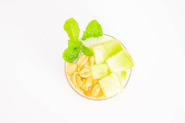 Mısır gevreğiyle kaplı kremalı muzlu smoothie ve beyaz arka planda temiz bardakta servis edilen taze nane şekeri. Yüksek kalite fotoğraf