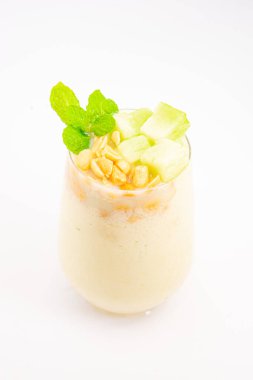 Mısır gevreğiyle kaplı kremalı muzlu smoothie ve beyaz arka planda temiz bardakta servis edilen taze nane şekeri. Yüksek kalite fotoğraf