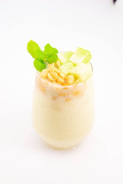 Mısır gevreğiyle kaplı kremalı muzlu smoothie ve beyaz arka planda temiz bardakta servis edilen taze nane şekeri. Yüksek kalite fotoğraf