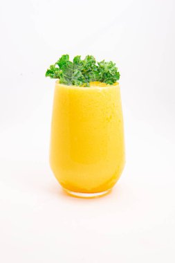 Sarı meyve suyu ya da şeffaf bardakta servis edilen ve temiz beyaz arka planda taze kıvırcık lahana ile süslenmiş meyve suyu. Yüksek kalite fotoğraf